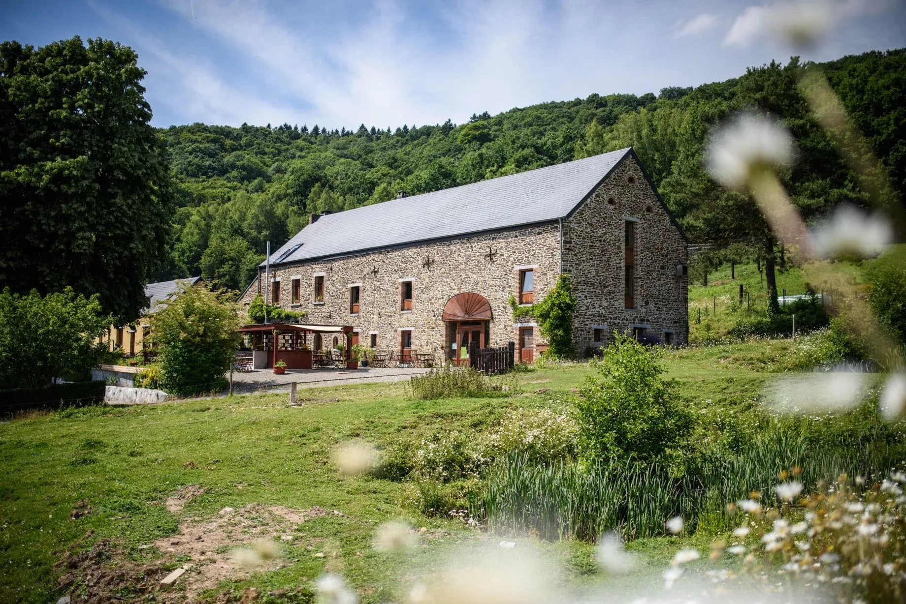 Le long bâtiment en pierre des 4 Sources, au pied d’une colline boisée